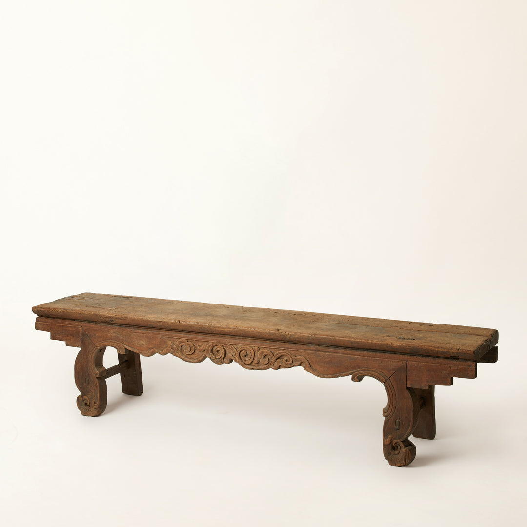 Wooden bench with intricate carvings on a white background