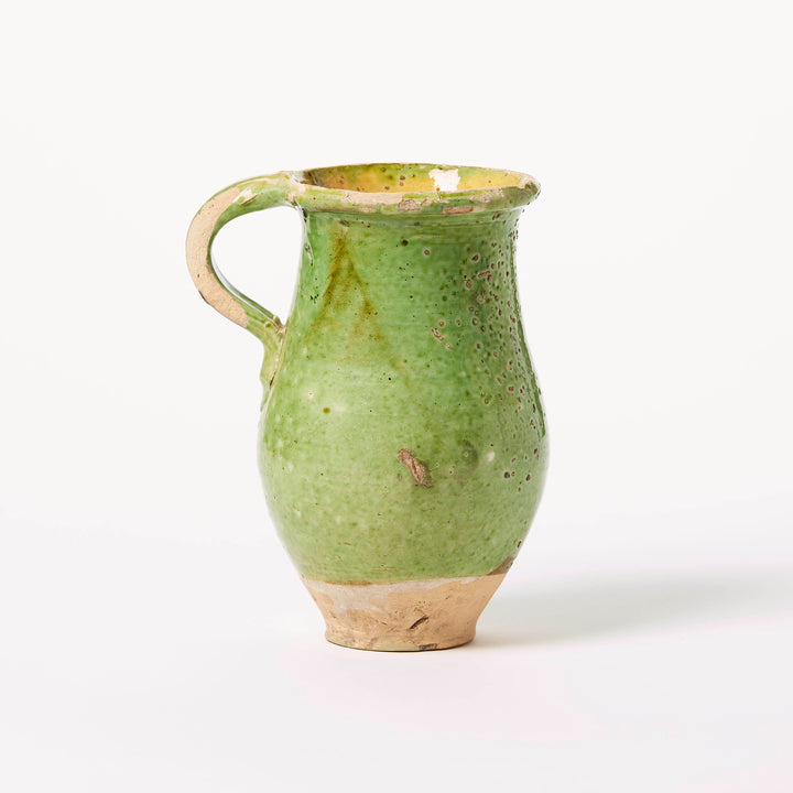 Green ceramic pitcher on a white background