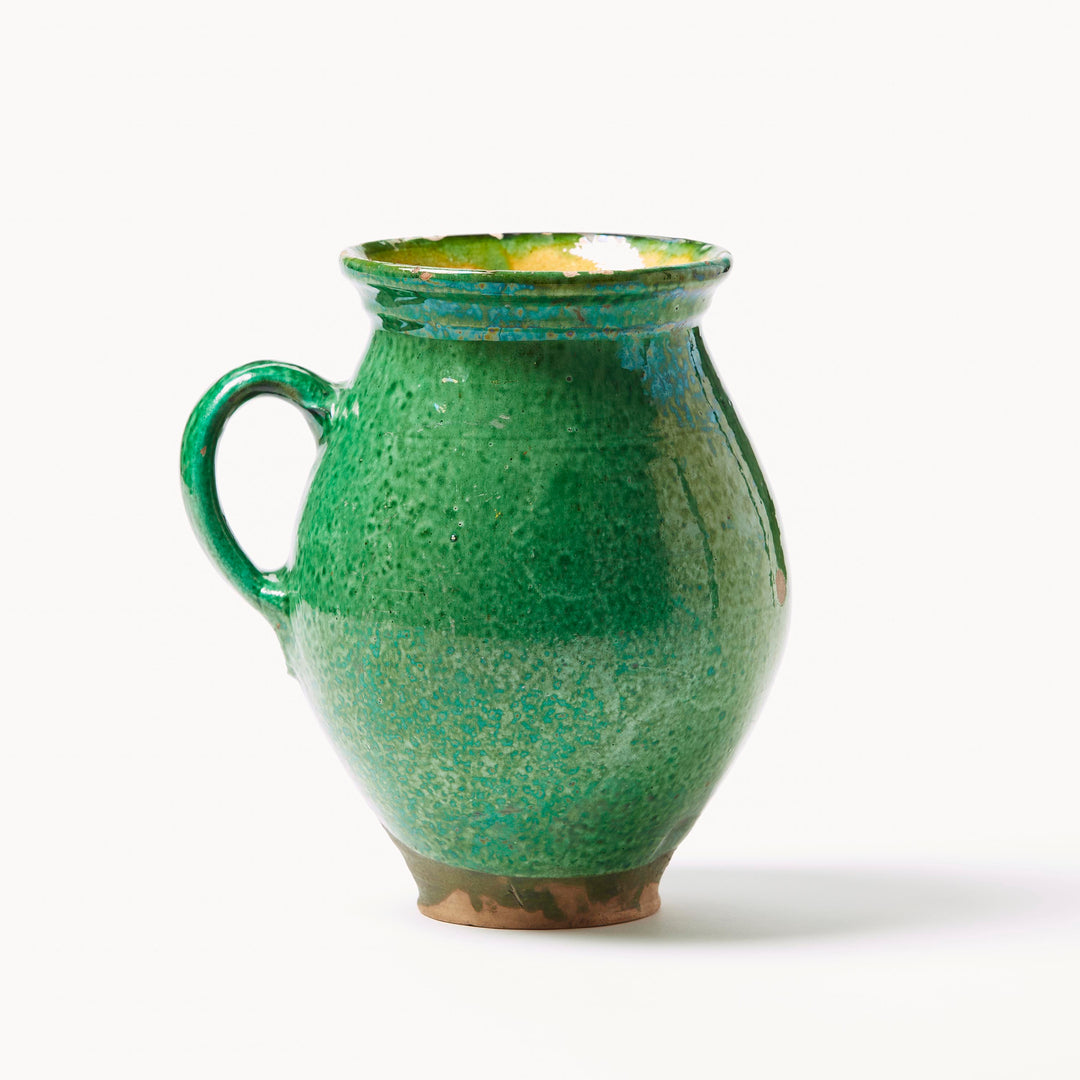 Green ceramic pitcher on a white background