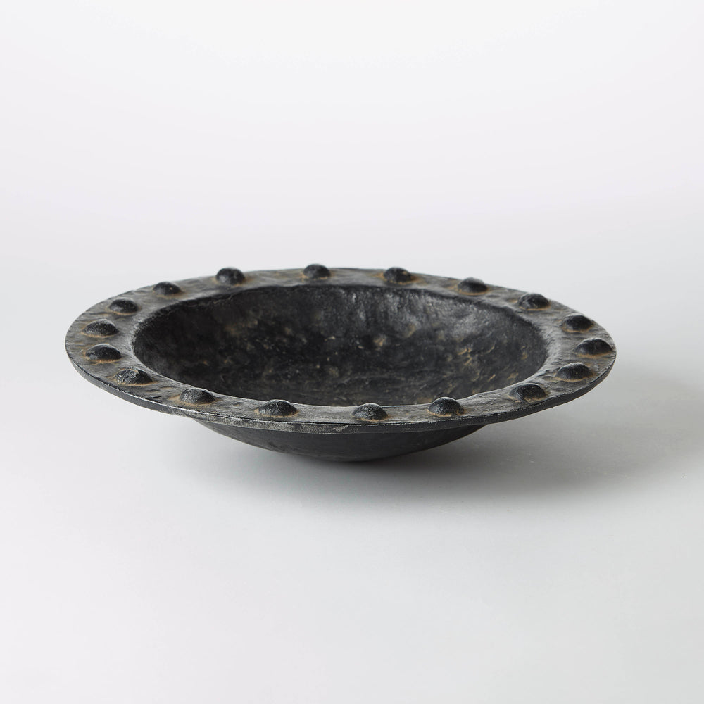 Textured black wax-cast iron bowl with a studded seeded rim and organic shallow profile.