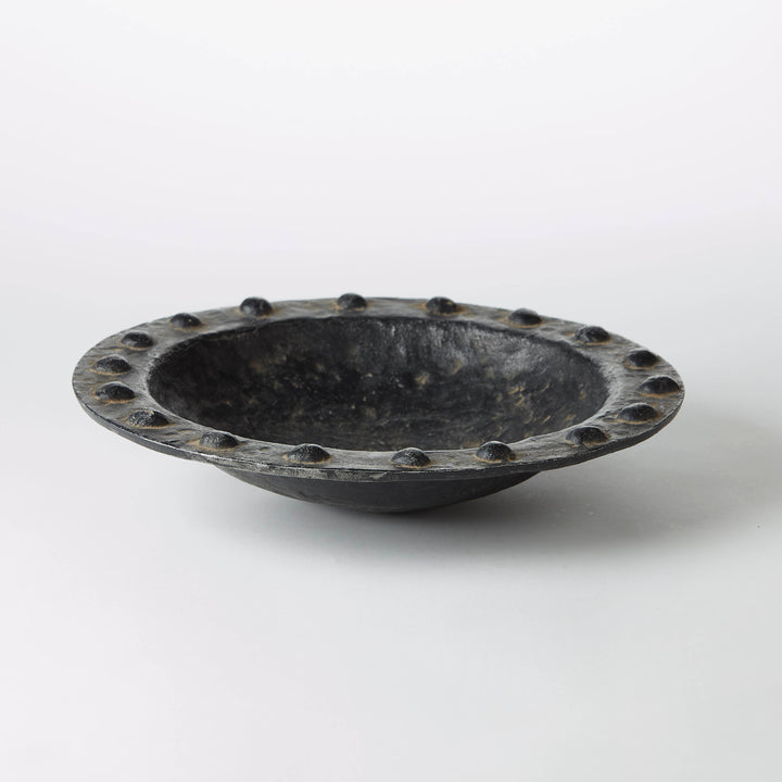 Textured black wax-cast iron bowl with a studded seeded rim and organic shallow profile.