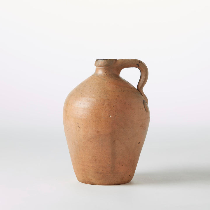 beige ceramic jar with a handle on a white background