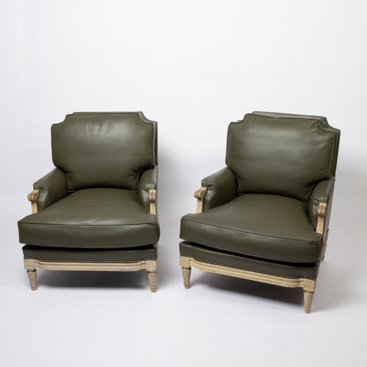 A pair of classic French-style armchairs upholstered in dark olive green leather with light beige painted wood frames, shown against a plain white studio background.
