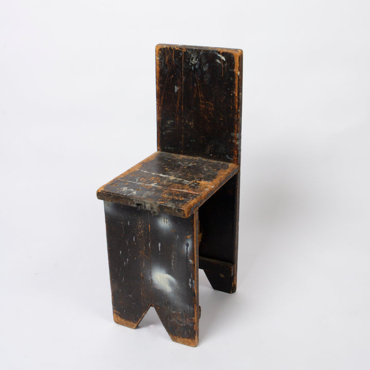 A small rustic wooden chair with a dark distressed finish and weathered brown edges, photographed on a clean white background.