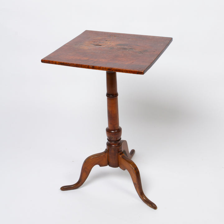 A small square wooden pedestal table candle stand with a turned central base and three curved legs, photographed on a clean white studio background.