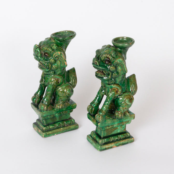 A pair of green glazed Chinese guardian lion statues with integrated cup holders on top, displayed against a plain white background.