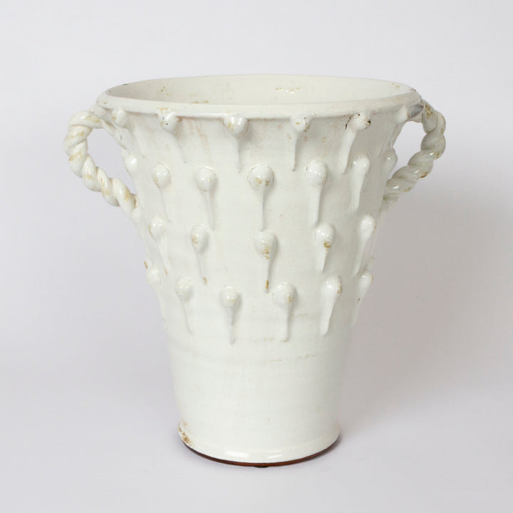A white ceramic vase with a textured, ribbed body featuring vertical raised dots and rope-style side handles, shown against a plain light gray background.