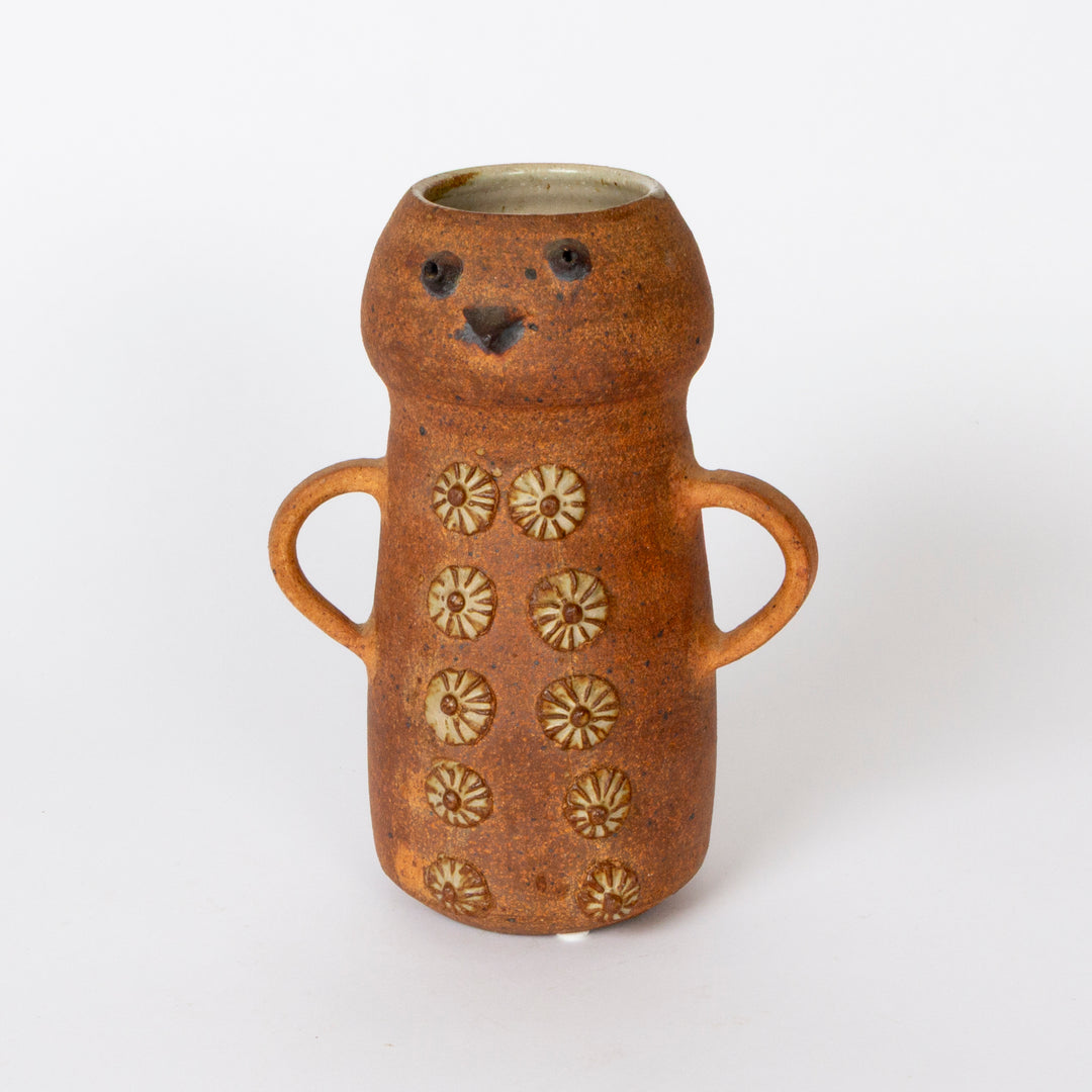 A handmade ceramic vase shaped like a bear, featuring a warm terracotta-brown glaze, two side handles, and raised floral patterns on the front, set against a plain white background.