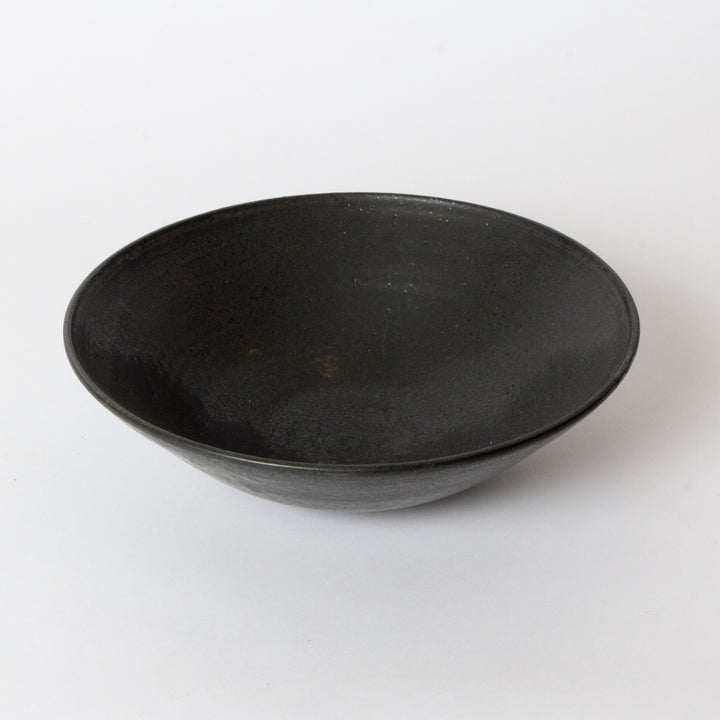 A dark charcoal gray black ceramic bowl with a textured, matte finish, photographed on a clean white background.