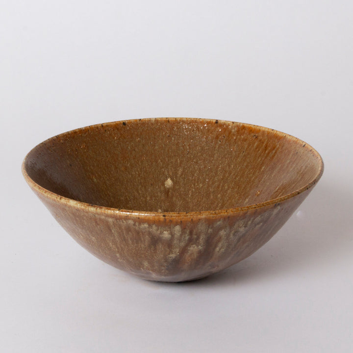 A handmade ceramic bowl with a textured, metallic bronze-brown glaze, photographed on a neutral light gray background.