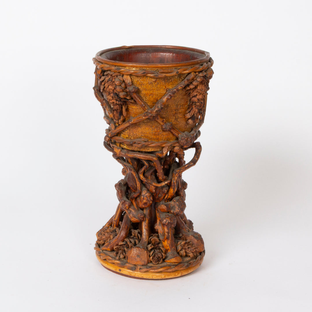 An ornate carved wooden goblet or cup with intricate sculpted details, including grape clusters and figures, shown on a plain white background.