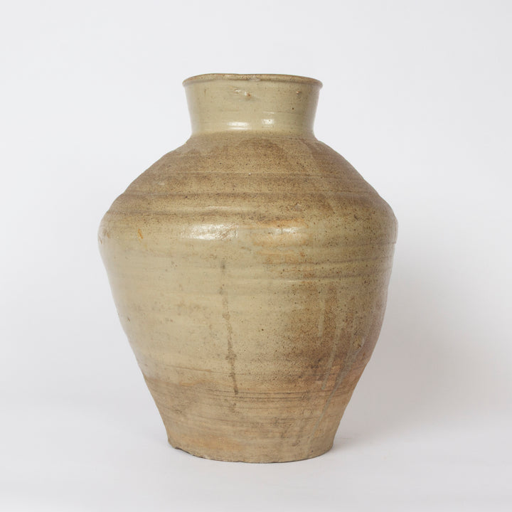 A handmade ceramic vase with a wide, rounded body, a narrow neck, and a flared rim, featuring a textured, horizontal hand-painted glaze in earthy beige and brown tones, set against a plain white background.