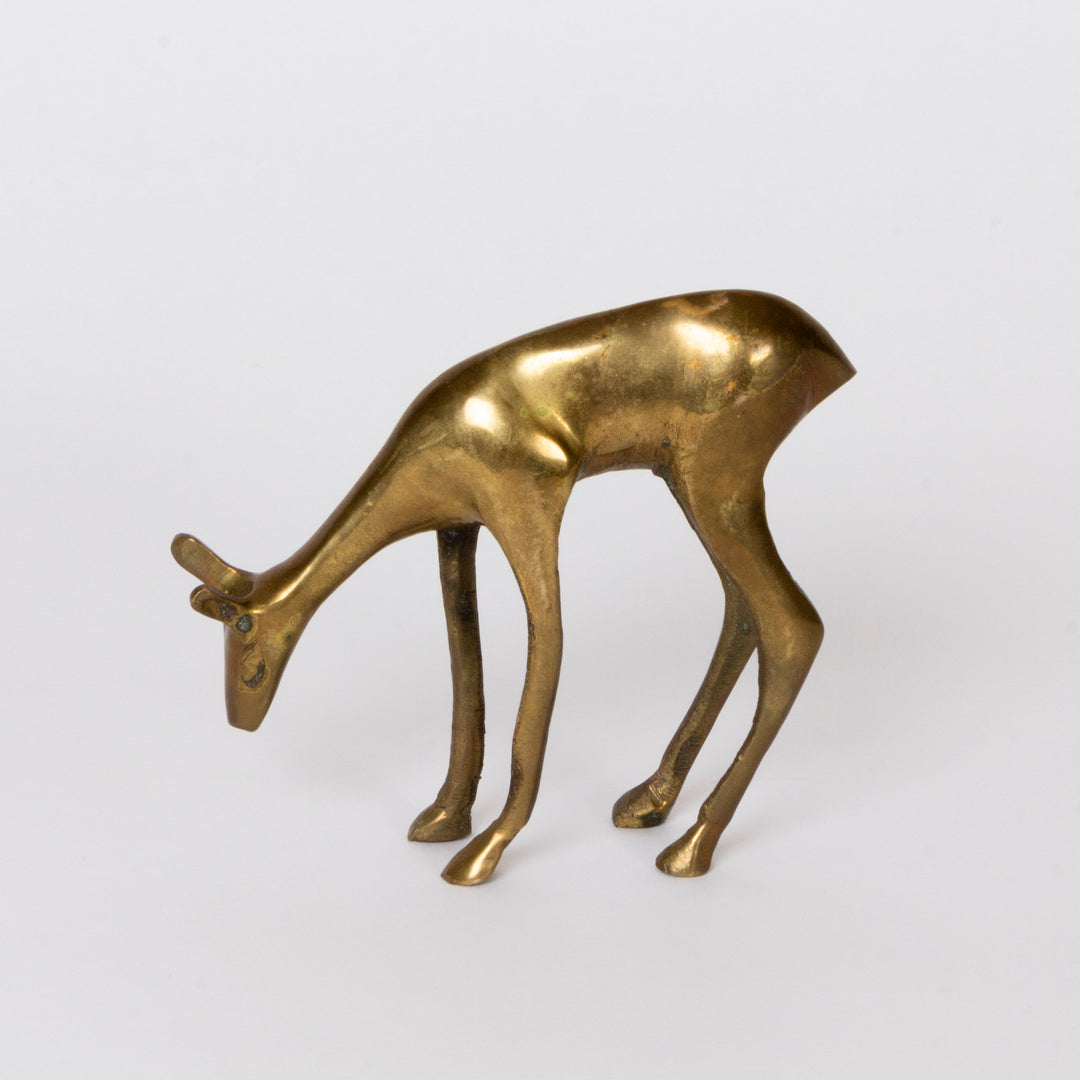 A small metallic deer figurine in a gold finish, shown from the side against a plain light gray background.