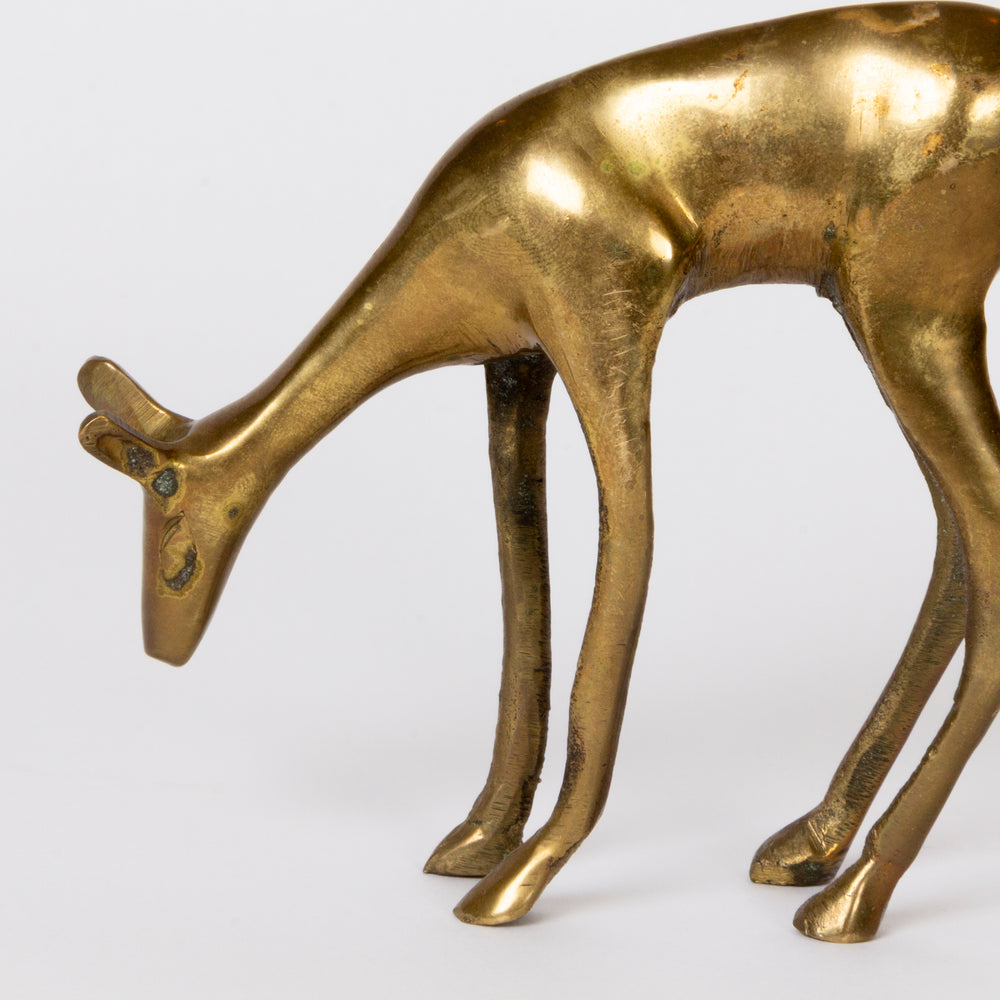 A close-up of a metallic deer figurine with a polished gold finish, captured against a clean white background.