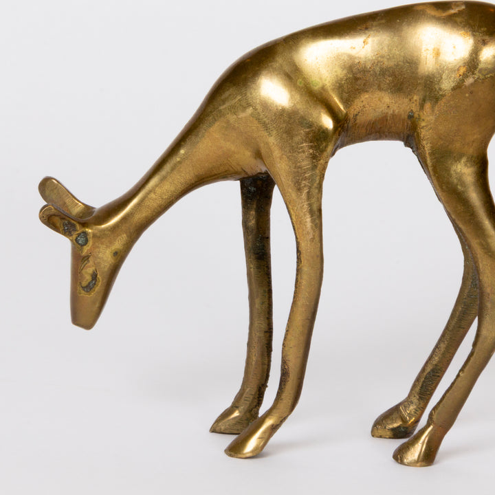 A close-up of a metallic deer figurine with a polished gold finish, captured against a clean white background.