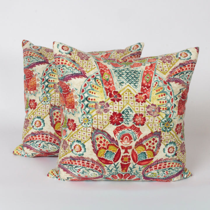 Two square decorative throw pillows with a vibrant, intricate multicolor paisley and floral pattern on a cream background, displayed against a clean white studio backdrop.