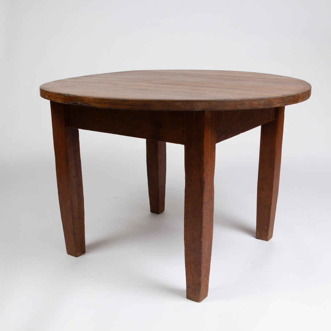 A round wooden dining table with four legs, photographed on a seamless white studio background.