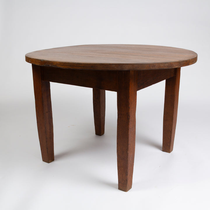 A round wooden dining table with four legs, photographed on a seamless white studio background.