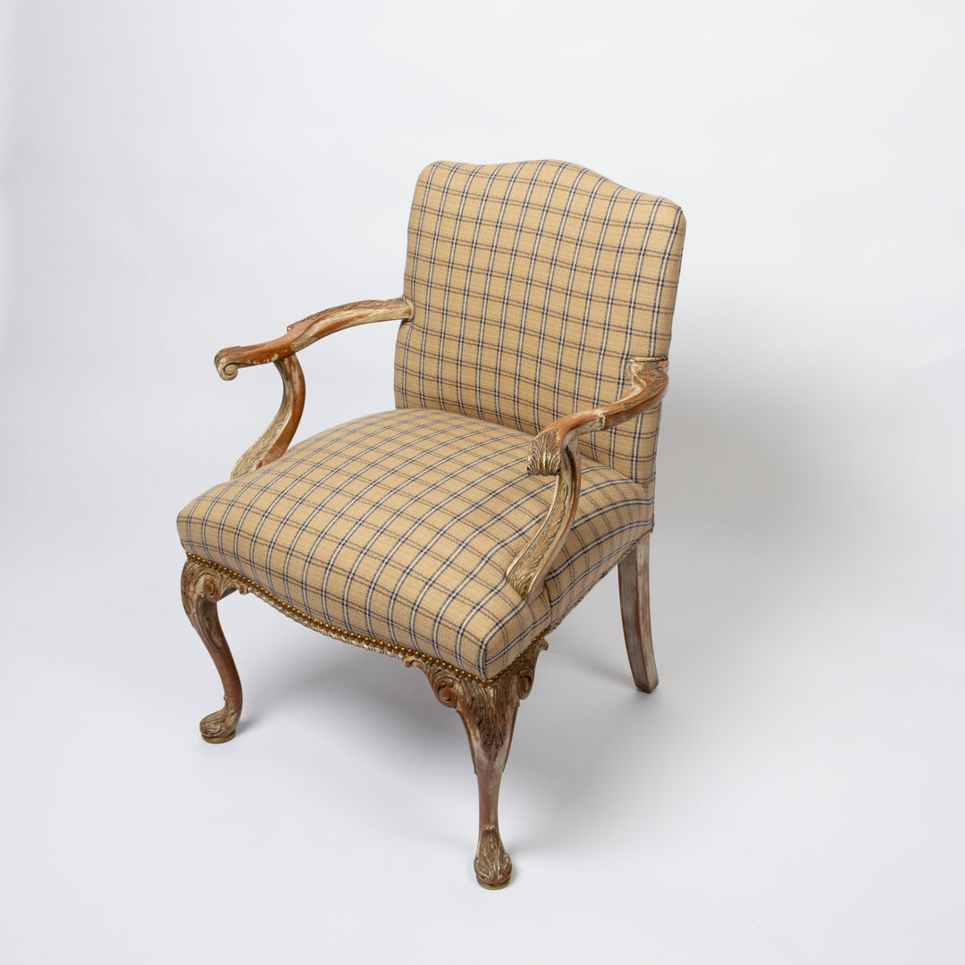 An antique-style French cabriole armchair with a beige and brown plaid upholstered seat and backrest, featuring carved wooden arms and legs with gold leaf detailing.