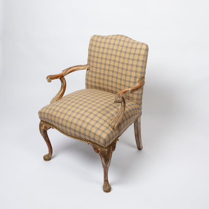 An antique-style French cabriole armchair with a beige and brown plaid upholstered seat and backrest, featuring carved wooden arms and legs with gold leaf detailing.