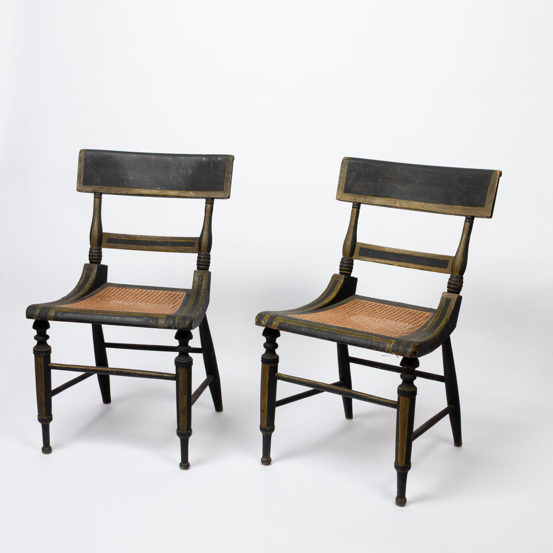 Two vintage wooden dining chairs with black painted frames and woven cane seats, shown on a white studio background.