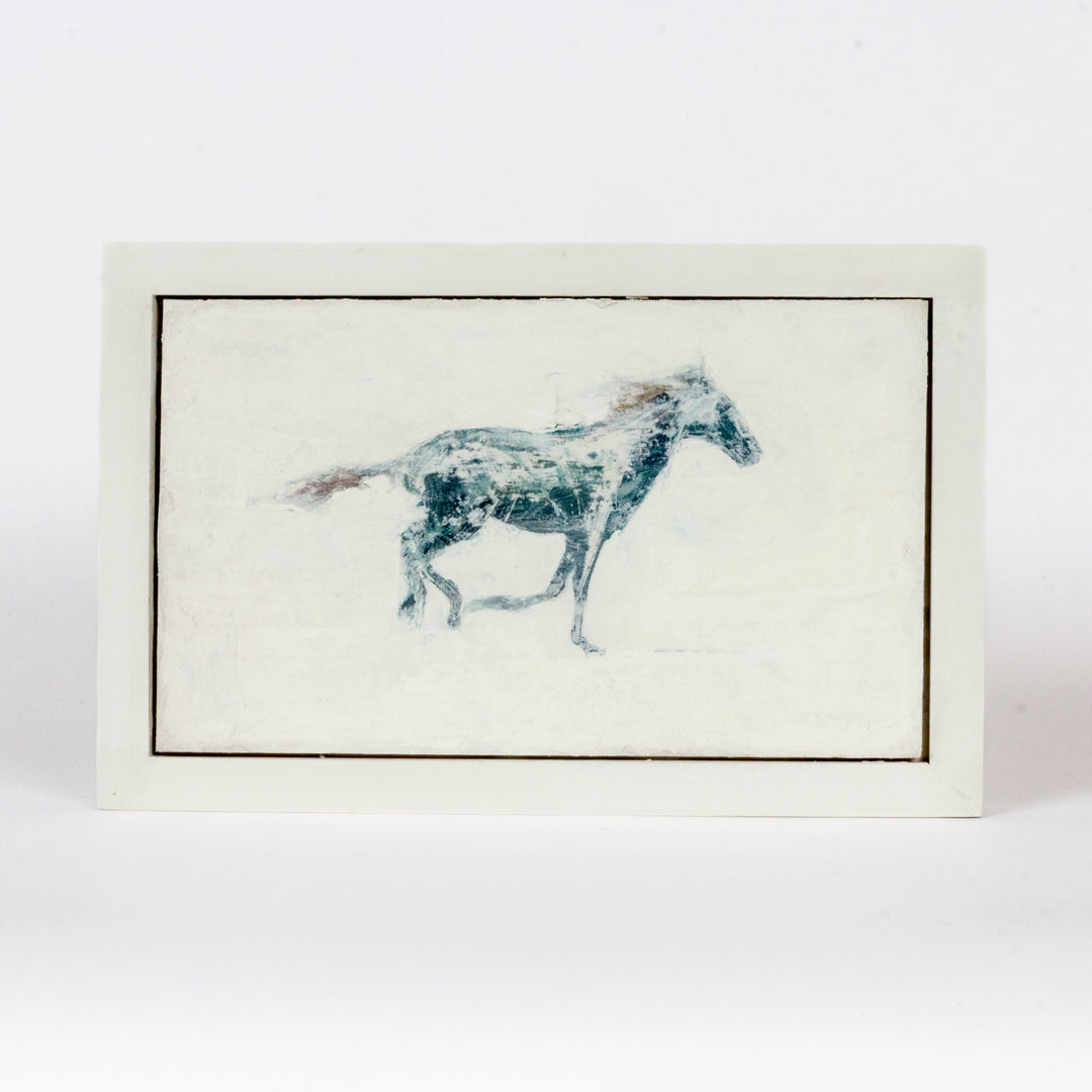 A rectangular framed art print featuring a blue and white painted horse on an off-white background, set against a plain white studio backdrop.